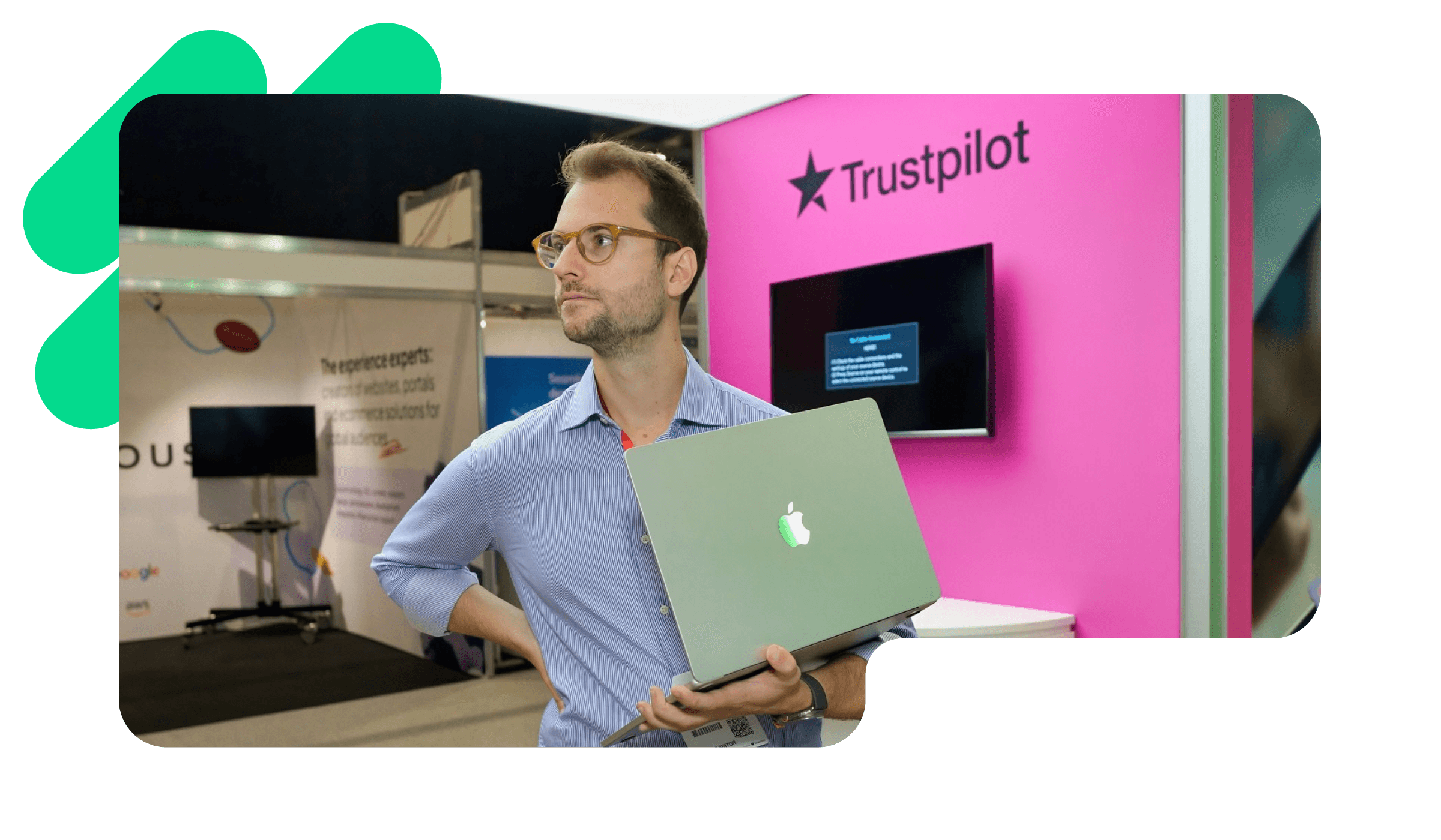 A photo of a Trustpilot employee standing in the Trustpilot office with his Macbook in his hands
